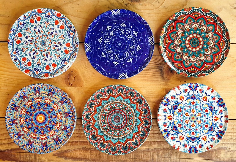 May include: Six decorative ceramic plates with intricate mandala designs in shades of blue, red, white, and yellow. The plates feature a variety of patterns and colors, creating a visually appealing and vibrant display.