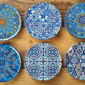 May include: Six round ceramic plates with blue and white geometric patterns. The plates have a variety of designs, including paisley, floral, and geometric shapes.