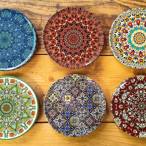 May include: Six decorative ceramic plates with intricate mandala designs. The plates feature a variety of colors, including blue, red, green, yellow, and white.