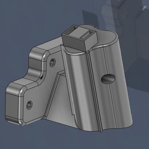 May include: A gray plastic part with a rectangular shape and a rounded edge. The part has a hole in the center and a smaller rectangular piece attached to the top.