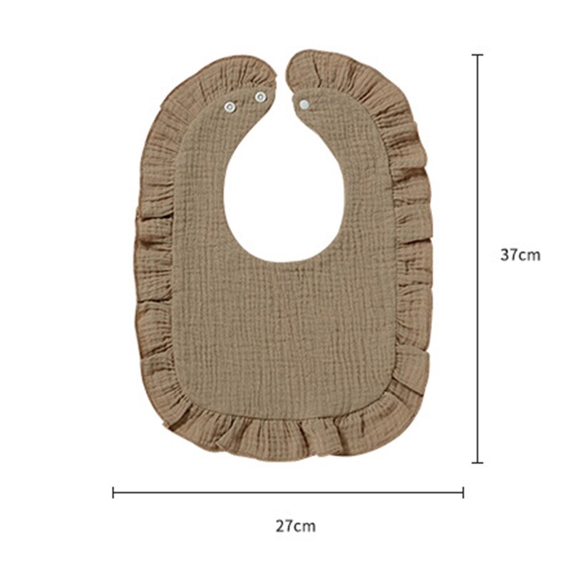 May include: A tan bib with a ruffled edge and two white snap closures at the neck. The bib features a textured fabric surface and measures 37 cm in height and 27 cm in width as indicated by the measurement lines and text printed on the image.