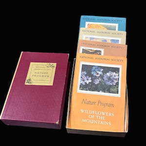 May include: A collection of vintage National Audubon Society Nature Program books. The books are in a box and a separate burgundy case. The book covers feature images of flowers and the text "Wildflowers of the Mountains".