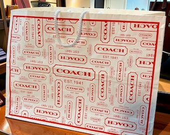 Bolsa de regalo vintage con asa superior y estampado del logo de Coach (2011), color rojo y blanco.
