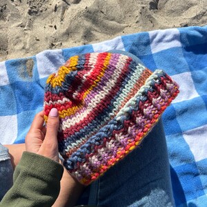 May include: A colorful striped knitted hat with a variety of colors including red, pink, yellow, blue, and white.
