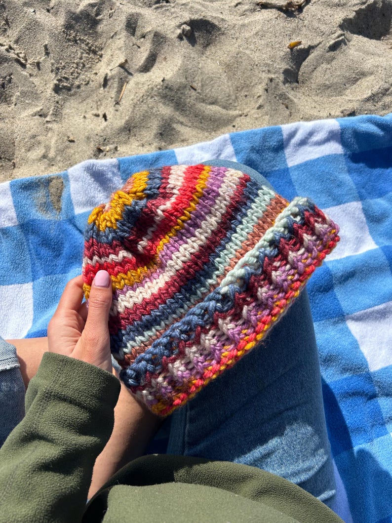 May include: A colorful striped knitted hat with a variety of colors including red, pink, yellow, blue, and white.