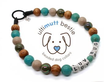 Puede incluir: Un collar de perro con cuentas turquesas, marrones y beige. El collar tiene cuentas blancas con letras que deletrean "LUV BUG". El logotipo "ultimutt bestie" está en el centro del collar.