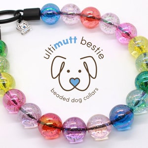 May include: Rainbow beaded dog collar with clear iridescent beads and a black adjustable buckle. The collar has a silver charm with a dog silhouette. The collar is labeled "ultimutt bestie beaded dog collars".