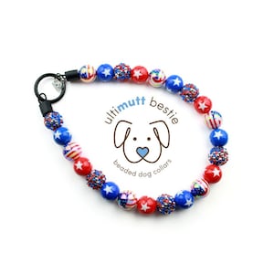 May include: Red, white, and blue beaded dog collar with a star pattern. The collar has a black clasp and is attached to a silver ring. The collar is labeled "ultimutt bestie beaded dog collars".