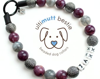 Puede incluir: Un collar de perro con cuentas con el nombre "JAX" escrito con cuentas de letras blancas. El collar presenta cuentas plateadas, grises y burdeos. También es visible el logotipo de la marca "ultimutt bestie".