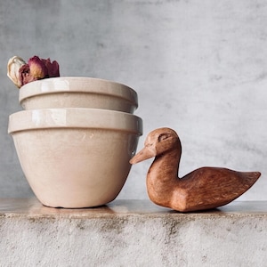 May include: A set of three ceramic mugs with a speckled, matte finish. The mugs are in shades of cream, light gray, and dark gray. Each mug has a simple, minimalist design and a rounded handle.