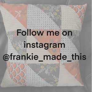 May include: A pillow with a patchwork design featuring geometric shapes and floral patterns in shades of orange, gray, and white. The pillow has the text "Follow me on instagram @frankie_made_this" printed on it.
