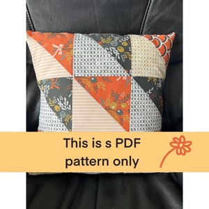 May include: A PDF pattern for a pillow with a patchwork design featuring orange, black, white, and gray fabric. The pillow is on a black leather couch. The text "This is a PDF pattern only" is on a yellow background.