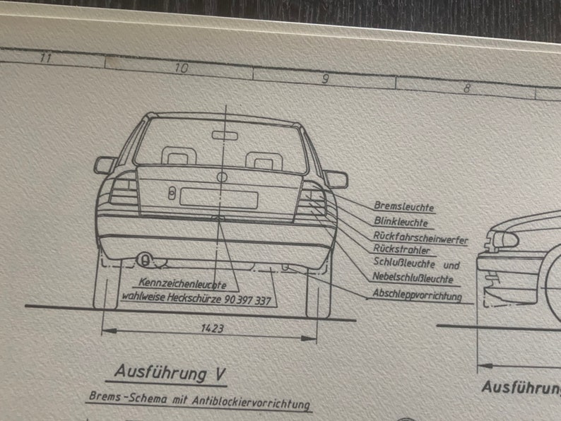 Puede incluir: Un dibujo en blanco y negro de la parte trasera de un coche con etiquetas para las diferentes luces, incluyendo las luces de freno, las luces de giro, las luces de marcha atr&aacute;s y las luces traseras. El texto "Ausf&uuml;hrung V" est&aacute; debajo del coche, y el texto "Brems-Schema mit Antiblockiervorrichtung" est&aacute; debajo de ese.