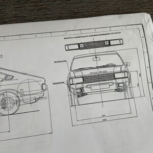 Puede incluir: Un dibujo en blanco y negro de una l&iacute;nea de un coche con la palabra "FORD" en la parrilla delantera. El dibujo est&aacute; en una hoja de papel blanca con medidas en cent&iacute;metros.