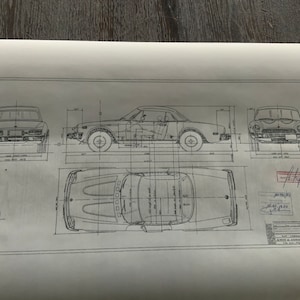 Op de afbeelding: Een technische tekening in zwart-wit van een auto, die de voor-, zij- en bovenaanzicht toont. De tekening bevat afmetingen in inches.
