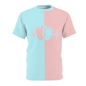 Puede incluir: Camiseta de manga corta dividida verticalmente en azul claro y rosa. El diseño presenta un par de huellas de bebé y un gráfico de latido cardíaco en el centro. La camiseta está hecha de un material suave y cómodo.