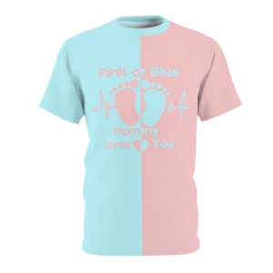Puede incluir: Una camiseta azul claro y rosa con el texto "Pink or Blue Mommy Loves You". La camiseta presenta un diseño dividido, con el lado izquierdo azul claro y el lado derecho rosa. El texto incluye huellas de bebé y una línea de latidos.