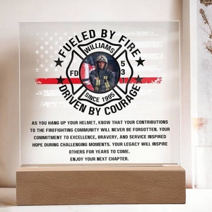 May include: A firefighter retirement gift with a red, white, and blue American flag background. The text reads "Fueled by Fire, Driven by Courage" with a firefighter's helmet and the words "Williams, FD, Since 1995".