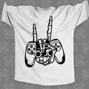 May include: A white t-shirt with a black graphic of a skeleton hand holding a video game controller. The skeleton hand is making the rock and roll hand gesture.