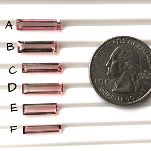 May include: Six pink and clear rectangular gemstones of varying sizes, labelled A to F, are arranged vertically on a white surface. A US quarter is included for size comparison.