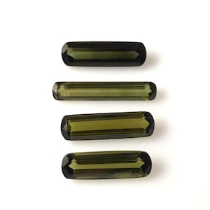 May include: Four green gemstone baguette cut stones, arranged vertically in a row.