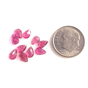 May include: A group of ten pink pear-shaped gemstones, each about the size of a ten pence coin.