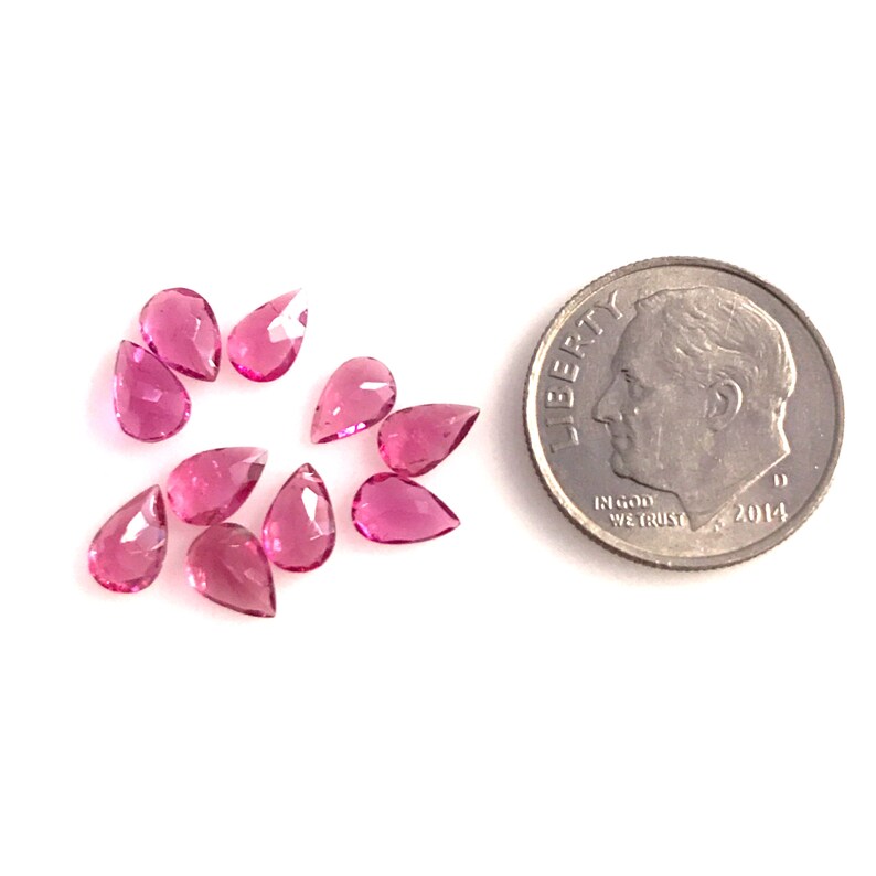 May include: A group of ten pink pear-shaped gemstones, each about the size of a ten pence coin.
