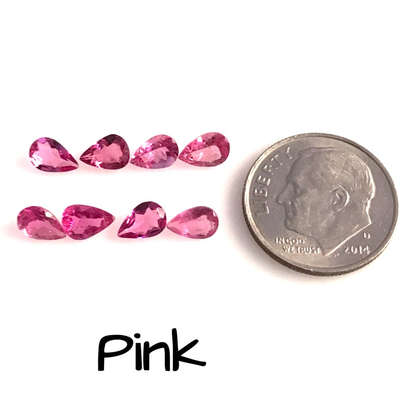 May include: Eight pink pear-shaped gemstones, each about the size of a 10 pence coin, arranged in two rows of four. A UK 10 pence coin is shown for scale.