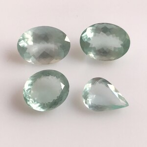 Puede incluir: Cuatro piedras preciosas de aguamarina, dos de forma ovalada y dos de forma de pera, con un tono verde claro.