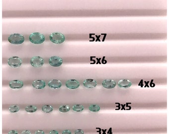 May include: Assortment of oval-shaped, light green gemstones arranged in rows on a white surface. The rows are labeled with numbers indicating the quantity of stones in each row, such as "5x7", "5x6", "4x6", "3x5", and "3x4".