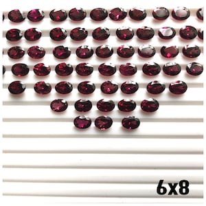 Puede incluir: Una colecci&oacute;n de 48 piedras preciosas ovaladas de color rojo oscuro dispuestas en forma de coraz&oacute;n sobre una superficie blanca. El texto "6x8" est&aacute; impreso en negro en la parte inferior de la imagen.