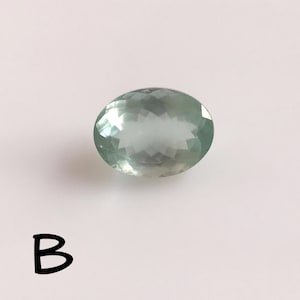 Puede incluir: Una piedra preciosa ovalada de color verde claro con un corte facetado.