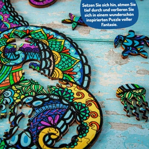 May include: A colorful wooden jigsaw puzzle featuring a seahorse and other sea creatures. The puzzle pieces are intricately designed with mandala-like patterns. The text on the puzzle reads: "Setzen Sie sich hin, atmen Sie tief durch und verlieren Sie sich in einem wundersch&ouml;n inspirierten Puzzle voller Fantasie."