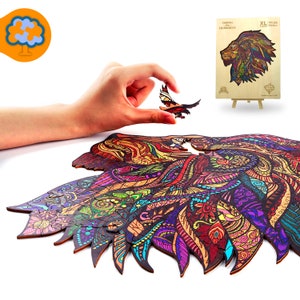 May include: A wooden jigsaw puzzle featuring a colorful lion design with intricate patterns. The puzzle is partially assembled, with a hand holding a small butterfly-shaped piece. A smaller, completed version of the lion puzzle is displayed on a miniature easel.