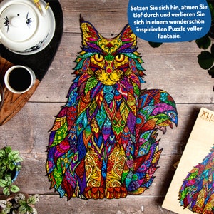 May include: A colorful jigsaw puzzle of a cat with intricate patterns and designs. The puzzle is made of wood and has a large number of pieces. The puzzle is on a wooden surface. The text on the box reads "Setzen Sie sich hin, atmen Sie tief durch und verlieren Sie sich in einem wundersch&ouml;n inspirierten Puzzle voller Fantasie." and "XL PUZZLES".