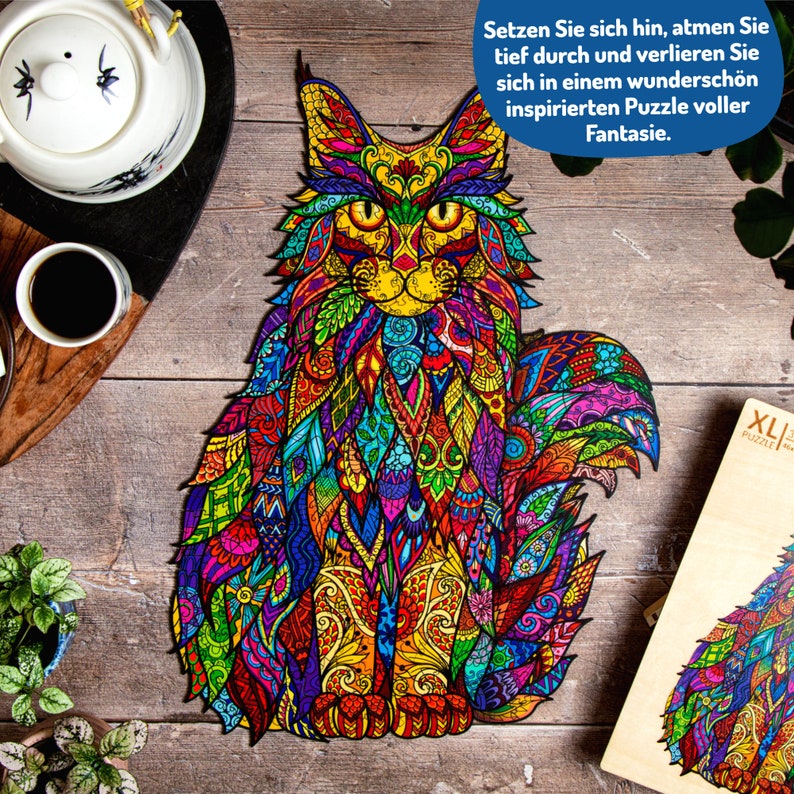 May include: A colorful jigsaw puzzle of a cat with intricate patterns and designs. The puzzle is made of wood and has a large number of pieces. The puzzle is on a wooden surface. The text on the box reads "Setzen Sie sich hin, atmen Sie tief durch und verlieren Sie sich in einem wundersch&ouml;n inspirierten Puzzle voller Fantasie." and "XL PUZZLES".