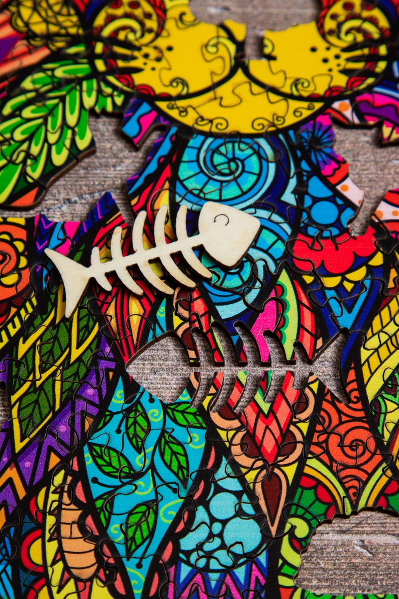 May include: A colorful jigsaw puzzle with a whimsical design featuring a cat and a fish bone. The puzzle pieces are arranged in a chaotic pattern, creating a vibrant and playful image.