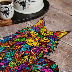 May include: A colorful wooden jigsaw puzzle of a cat with intricate patterns and designs. The puzzle pieces are cut in a unique way, creating a detailed and vibrant image.