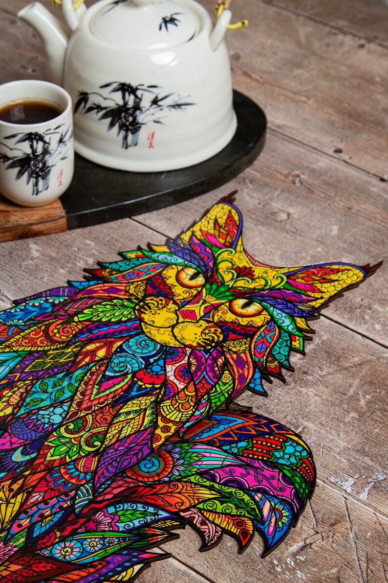 May include: A colorful wooden jigsaw puzzle of a cat with intricate patterns and designs. The puzzle pieces are cut in a unique way, creating a detailed and vibrant image.