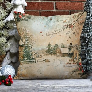 May include: A decorative throw pillow with a vintage-style illustration of a snowy winter scene. The pillow features a quaint village with houses, trees, and a winding road. The background is a soft, muted palette of browns, blues, and whites.