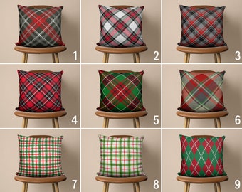 May include: Nine different throw pillow designs featuring various plaid patterns in red, green, white, and black. The pillows are displayed on chairs with wooden frames.
