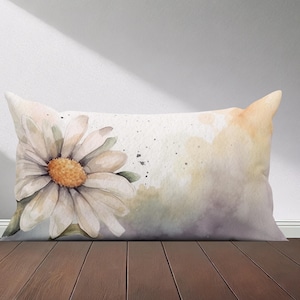 Peut inclure: Un oreiller blanc avec un motif aquarelle d'une marguerite avec un centre jaune. L'arri&egrave;re-plan est une douce aquarelle jaune et violette.