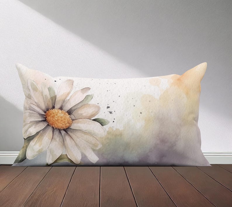 Peut inclure: Un oreiller blanc avec un motif aquarelle d'une marguerite avec un centre jaune. L'arri&egrave;re-plan est une douce aquarelle jaune et violette.