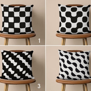 May include: Four black and white patterned throw pillows on brown chairs. The pillows feature geometric designs with alternating black and white squares, circles, and curved shapes.