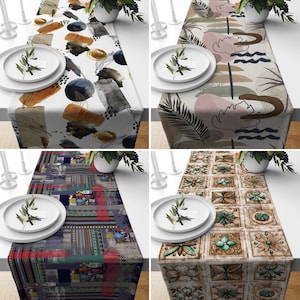 May include: Four different table runners with various patterns. The first runner has a white background with abstract shapes and colors. The second runner has a beige background with a floral pattern. The third runner has a dark blue background with a geometric pattern. The fourth runner has a beige background with a tile pattern.