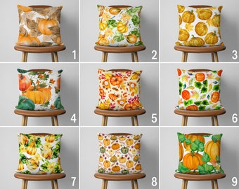 Könnte beinhalten: Neun verschiedene Kissen-Designs mit Aquarell-Illustrationen von Kürbissen, Kürbissen und Blättern in Orange-, Gelb-, Grün- und Brauntönen. Die Kissen sind in einem Raster auf Stühlen angeordnet.