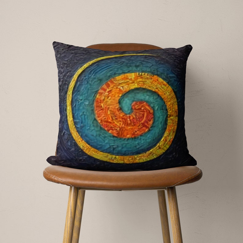 May include: A decorative throw pillow with a colorful spiral design. The spiral is made up of shades of blue, orange, and yellow, and is outlined in gold. The pillow is on a brown chair.