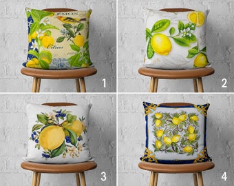 Peut inclure: Quatre designs de coussins différents mettant en scène des citrons et des agrumes. Les coussins sont présentés sur des chaises brunes sur fond de mur en briques blanches. Le premier coussin présente une illustration vintage de citrons, un oiseau et le texte "Lemon Citrus". Le deuxième coussin présente une illustration aquarelle de citrons sur une branche. Le troisième coussin présente une illustration aquarelle de citrons sur une branche avec des myrtilles. Le quatrième coussin présente un motif de carrelage bleu et blanc avec des citrons.