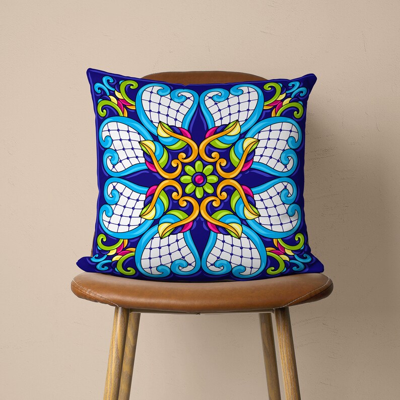May include: A blue cushion with a colourful, intricate floral design. The cushion features a repeating pattern of flowers, leaves, and swirls in shades of yellow, green, pink, and blue.