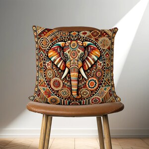 May include: A decorative throw pillow with a colorful, intricate design featuring an elephant's head in the center. The elephant is surrounded by geometric patterns and floral motifs in shades of orange, red, blue, and green.